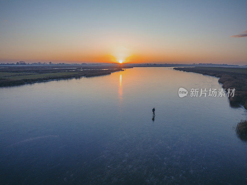 在美丽的冬日夕阳下，荷兰的湖面上滑冰