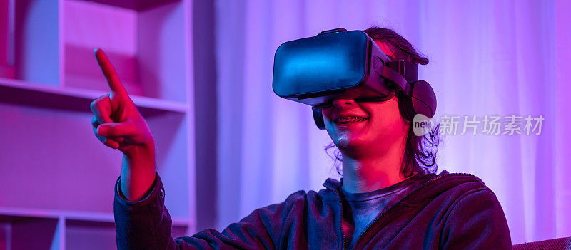 戴着虚拟现实(VR)眼镜的年轻人正在一个有红蓝灯的房间里玩游戏，兴奋地玩3D游戏，未来游戏，小工具，技术，VR游戏概念