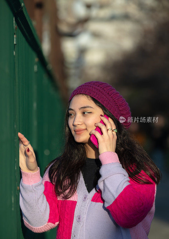 美丽的年轻女孩正在和别人讲她的手机。