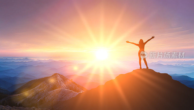 当太阳开始落山时，站在山顶的女人。成功商业领导。目标、希望和抱负的概念。日出山背景上的女性剪影