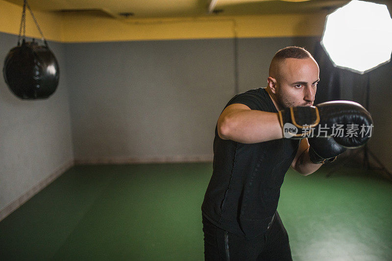 穿着运动服的男拳手在健身房独自训练，为拳击比赛做准备