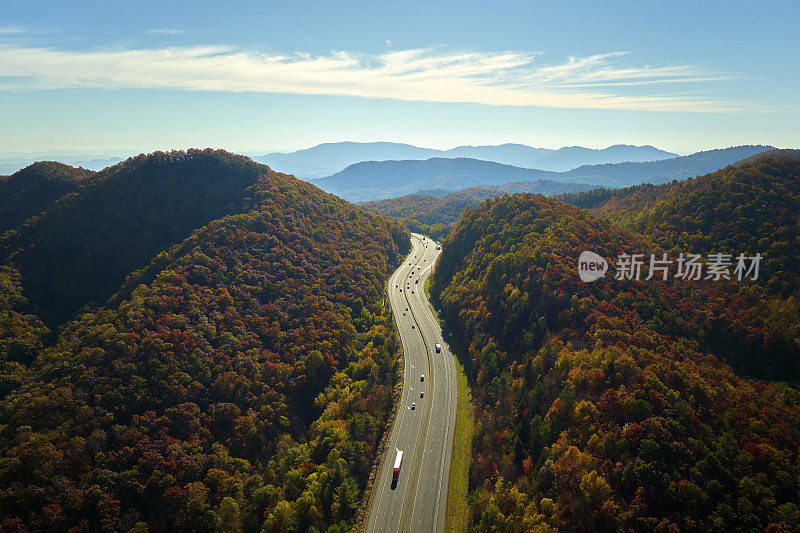 通往北卡罗来纳州阿什维尔的I-40高速公路穿过阿巴拉契亚山脉，那里有黄色的秋天森林和快速移动的卡车和汽车。高速州际交通的概念