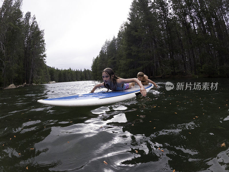 母亲和孩子们在湖上玩桨板