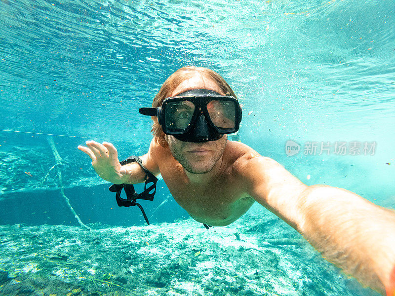 男子在清澈的水中游泳时在水下自拍