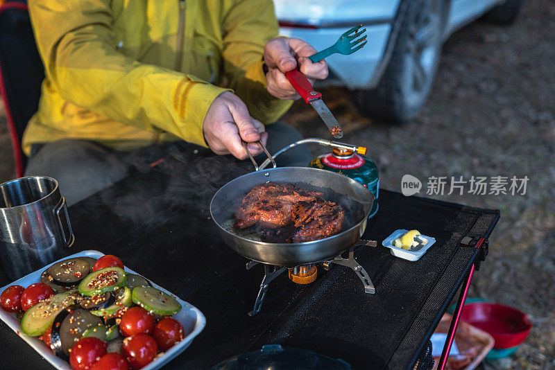 一名男子在森林中的露营地使用旅游燃烧器做饭