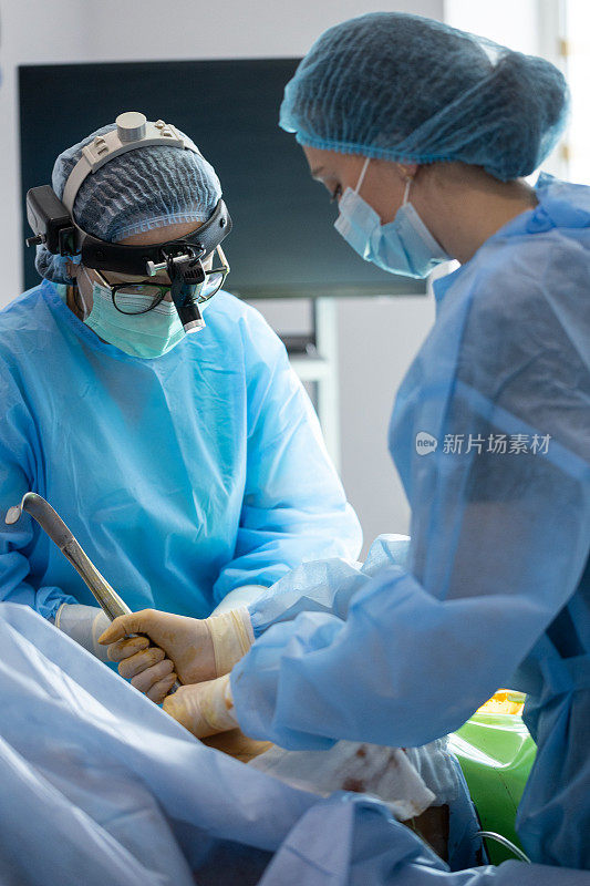 整形外科医生和手术室护士在一个女人的乳房上做手术。