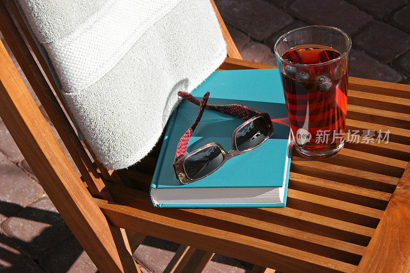 泳池边的老式书，太阳镜和饮料