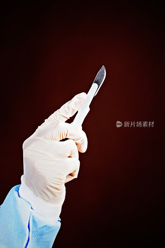 黑色背景上戴着手套的医务人员手持手术刀
