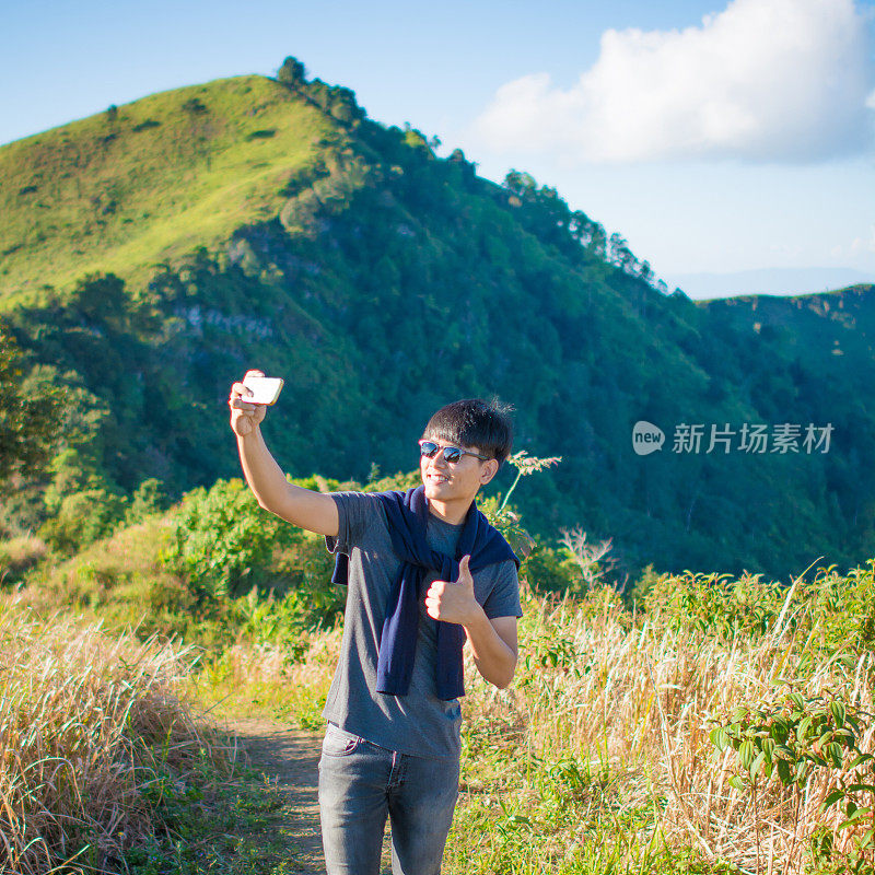 年轻的旅行者站在山上望着夕阳。