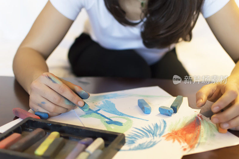 美丽的女人用彩色粉笔作画，孤立在白色的背景上