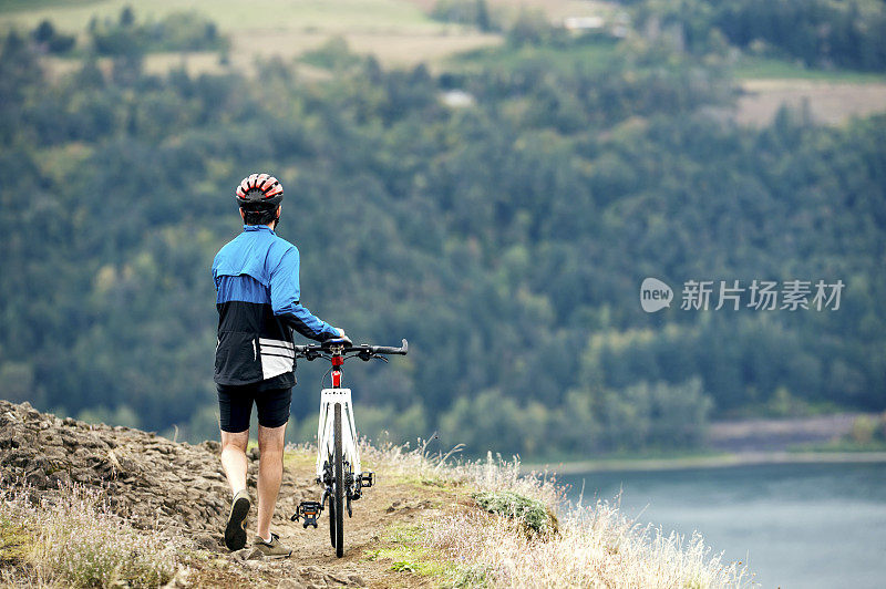 男性步行自行车沿山脊步道俯瞰水