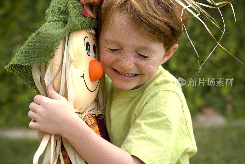 雀斑脸红头发的孩子，快乐的男孩拥抱万圣节稻草人和服装