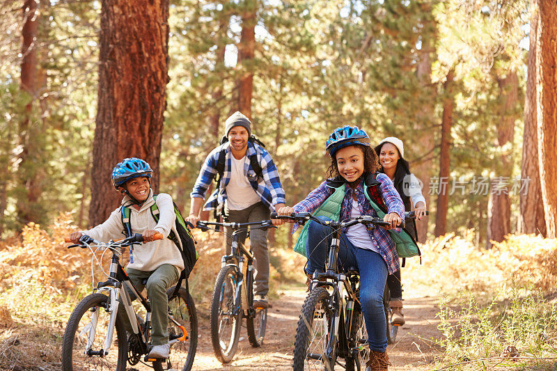 骑自行车穿越秋天林地的非裔美国家庭