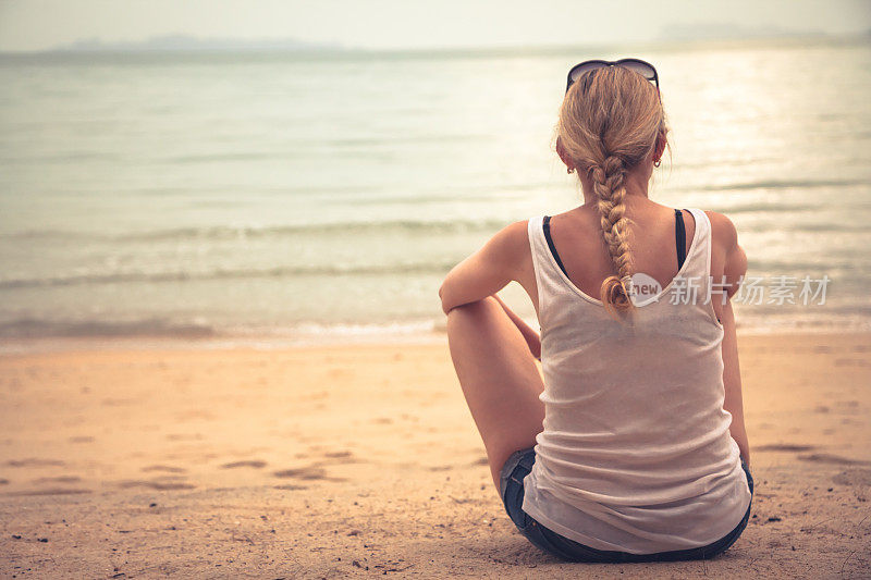 沉思的年轻女游客坐在海滩上放松