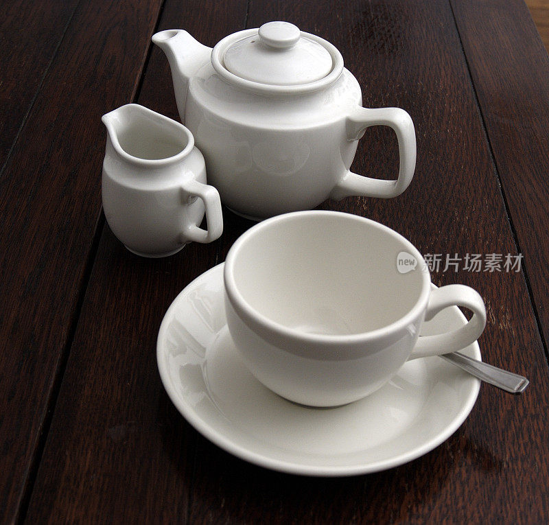 茶具，茶杯，茶碟，壶放在橡木桌子上。