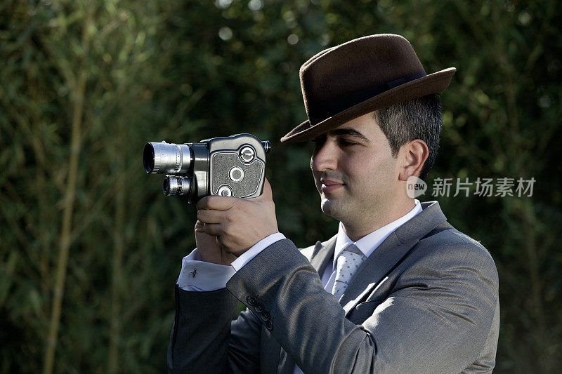 戴着帽子的年轻人通过老式的8毫米摄像机拍摄