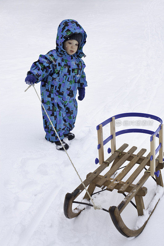 蹒跚学步的孩子在雪地里拉雪橇
