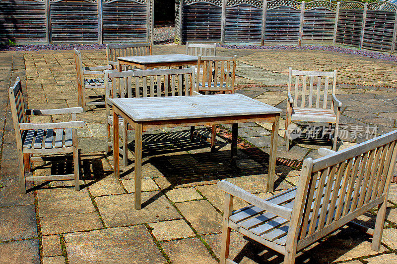 庭院中木制的花园桌子、椅子和长凳的形象