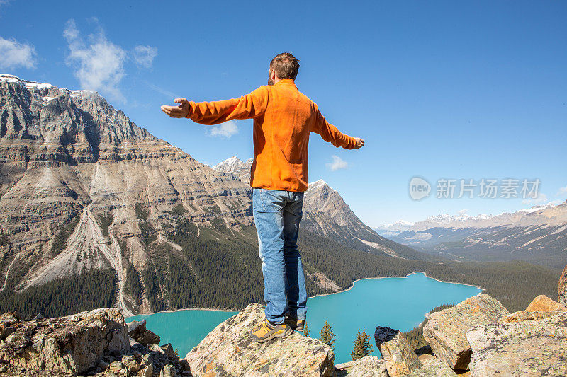 徒步旅行的年轻人站在山上，双臂张开