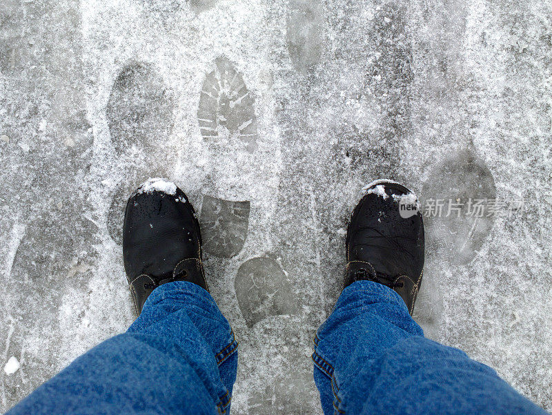 脚踩在雪地里的柏油路上。