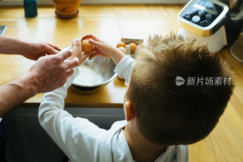 快乐的父亲和儿子在一起准备食物的时候玩