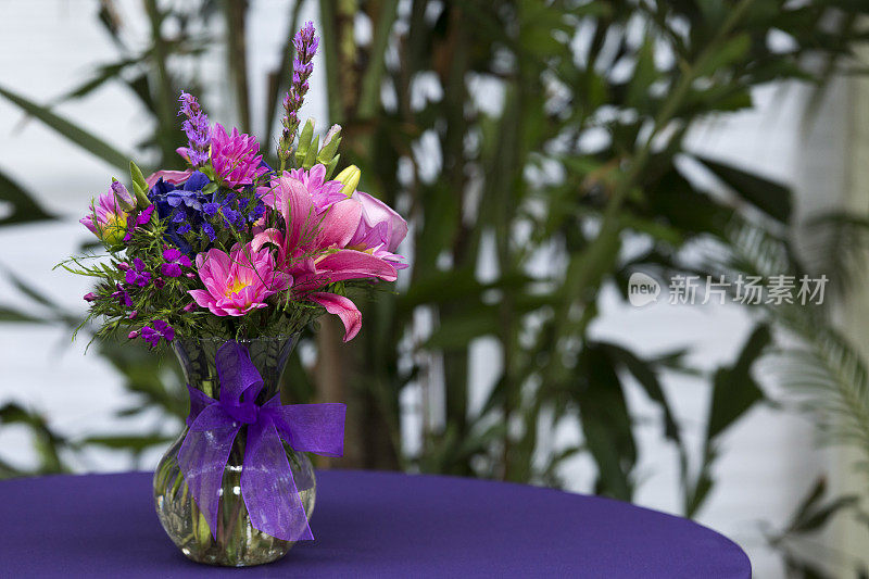 紫色的桌面上放着一瓶切花