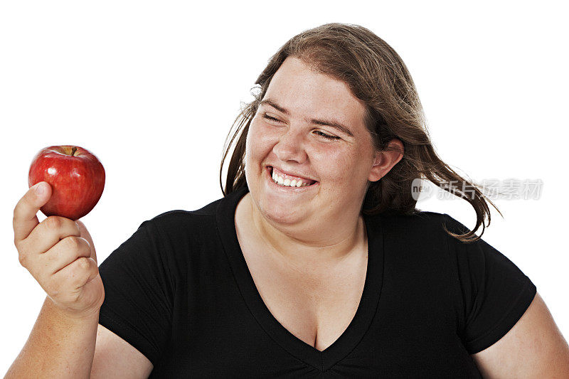 快乐超重的年轻女子笑眯眯地看着一个红苹果
