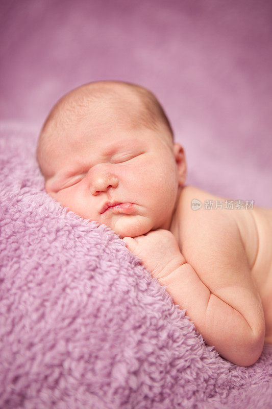 刚出生的女婴安静地睡在紫色的毯子上