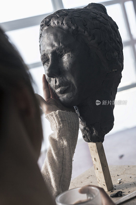 雕刻家手握泥塑脸颊