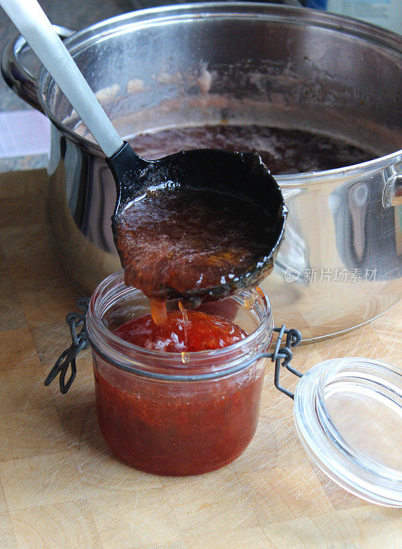 热草莓酱被舀进消过毒的玻璃果酱罐里