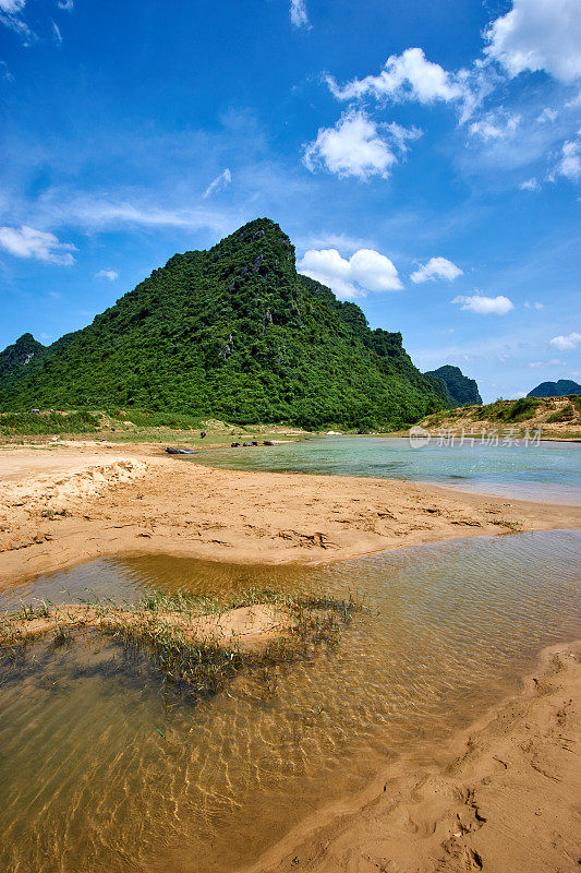 在越南丰年喀邦国家公园清澈的河流中，水牛。以大山和蓝天为背景。