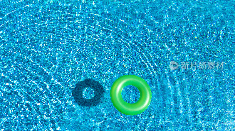 鸟瞰图的彩色充气圈甜甜圈玩具在游泳池的水从上面，家庭度假的概念背景
