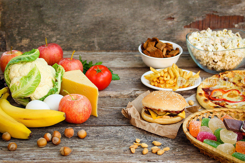 快餐和健康食品在旧的木制背景。概念选择正确的营养或垃圾食品。