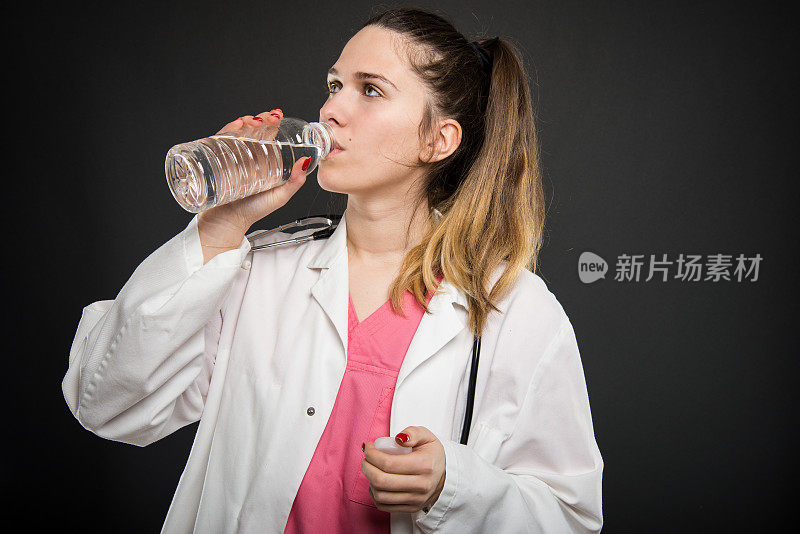 年轻女医生喝着一瓶水