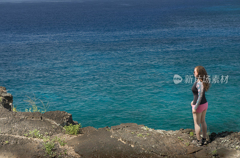 旅行中的美国女人沿着夏威夷海边的悬崖行走