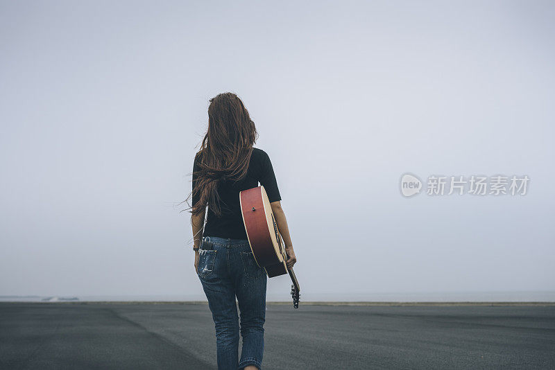 年轻女子拿着吉他在天空中行走