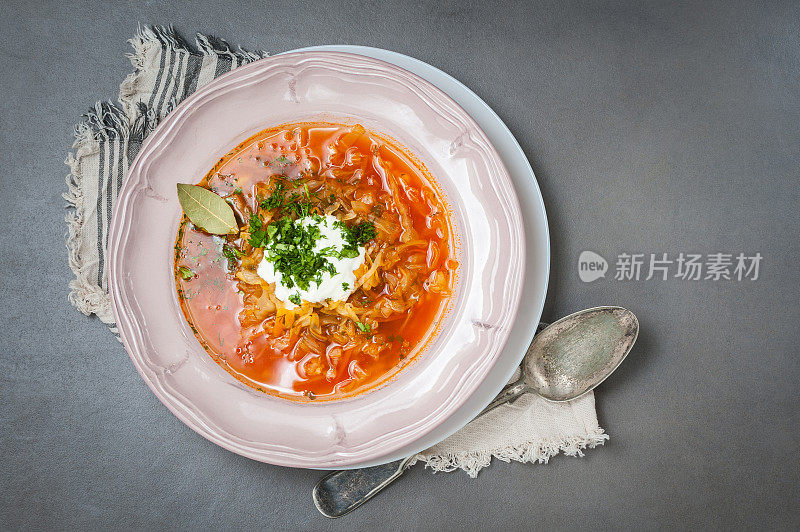 灰色的石头桌子上，老式盘子里装着卷心菜汤和西红柿。