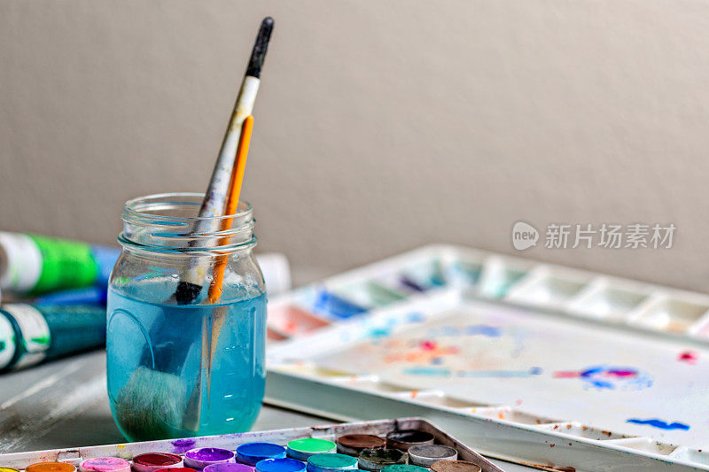 水彩和丙烯颜料-调色板和油漆刷在水。