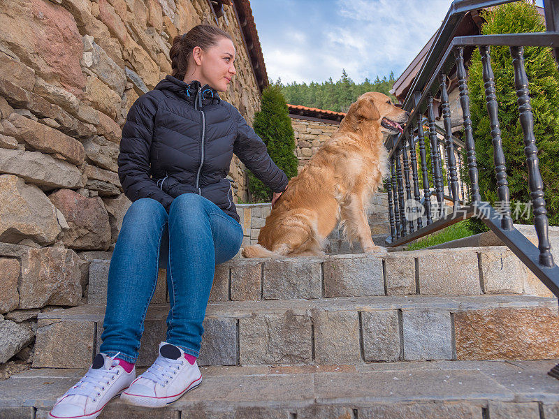 女孩和她的金毛猎犬坐在石阶上