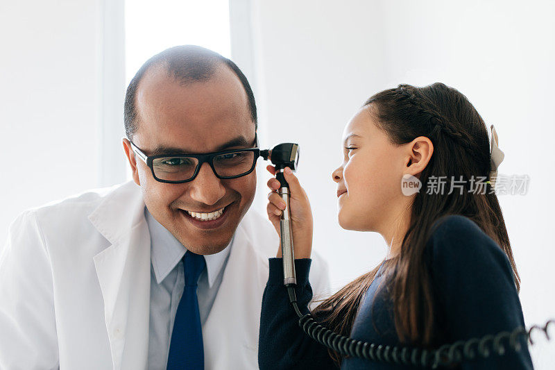 顽皮的女孩用耳镜看医生的耳朵