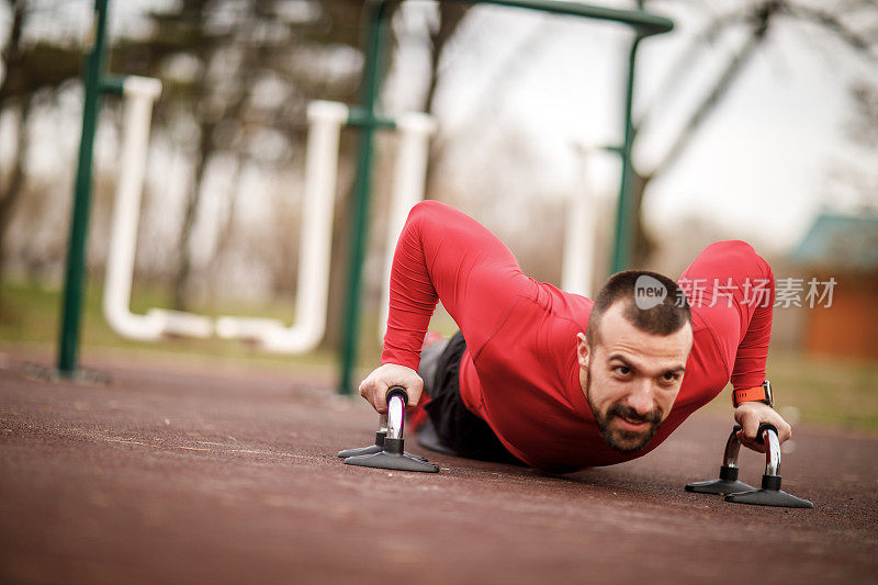 一个肌肉发达的运动员在城市公园里用抓地力做俯卧撑锻炼