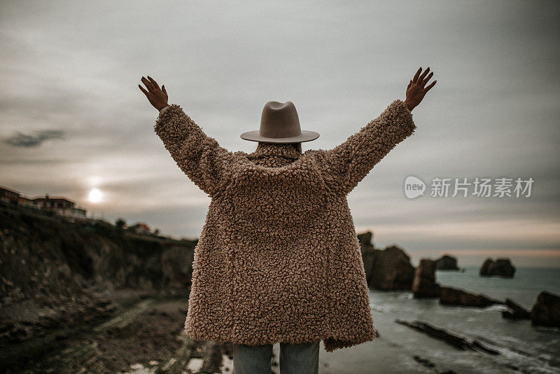 年轻的女人在海边举起双手