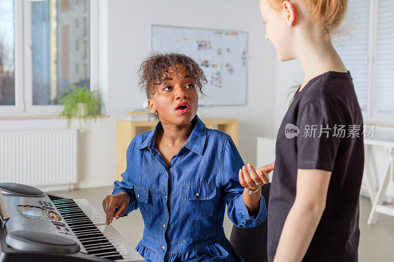 教练带着钢琴教女孩在课堂上唱歌