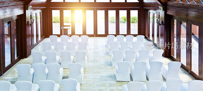 在室内举行婚礼，有一排白色的椅子