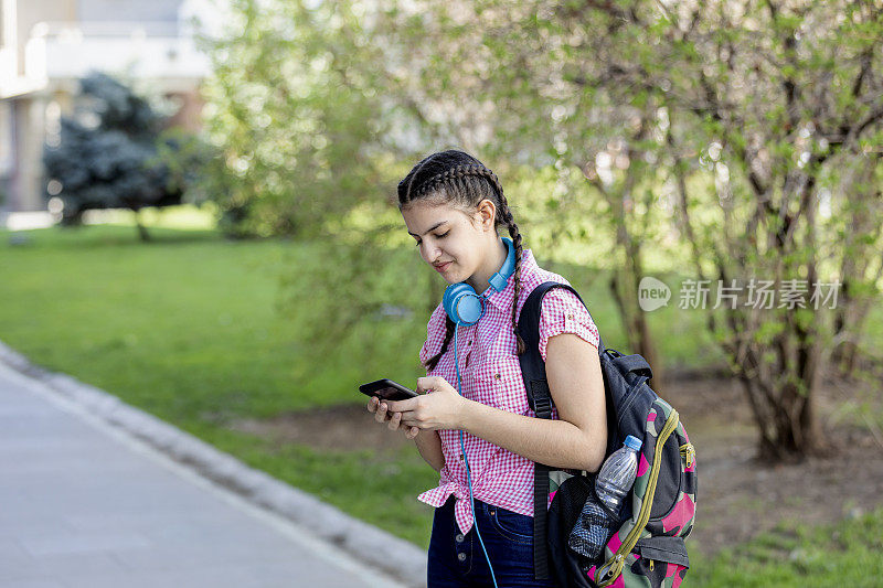 美丽的年轻女孩在户外使用她的手机