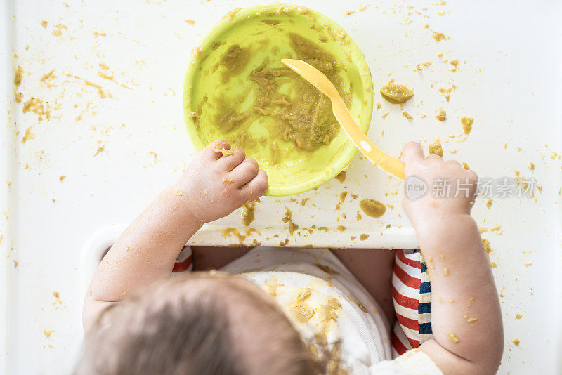 女婴在喂食椅上吃东西的高角度照片