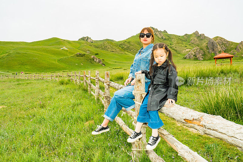 母亲和女儿坐在木栅栏上