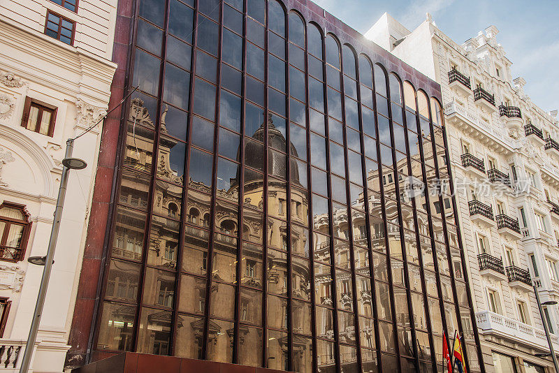 旧建筑反射在玻璃办公大楼的外立面上