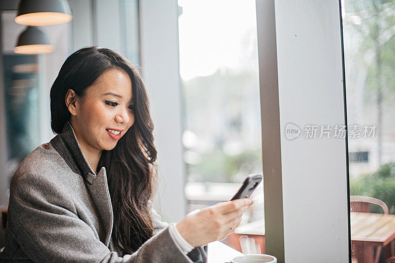 一名年轻女子在咖啡店里使用手机