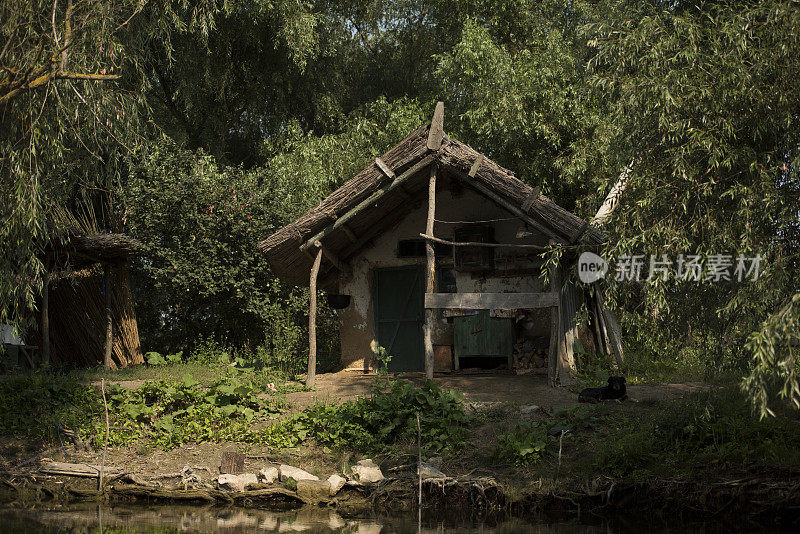 一个阳光明媚的夏日，罗马尼亚多瑙河三角洲一条河道上的老木屋